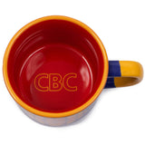 Overhead shot of CBC Logo mug. Inside of mug is dark orange with the text "CBC" outlined in yellow on the bottom of the mug.