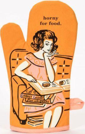Orange oven mitt with retro illustration of glamorous housewife seated on a couch with a pile of cookbooks, gazing at the one open in her lap. Text above her head reads "horny for food."